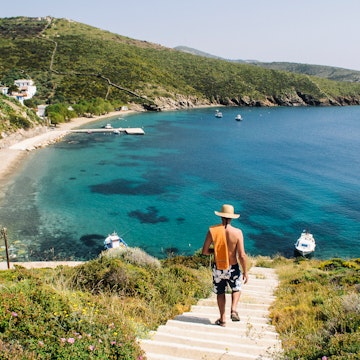 Rear view of a man walking down to a beach on Fourni Island, Greece.